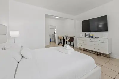 a white bedroom with a white bed and a tv at Stay in Brickell near Kaseya Center & South Beach in Miami