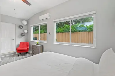 a bedroom with a white bed and a red chair at Charming Hideaway Near Beach, Nightlife & Shops in Fort Lauderdale