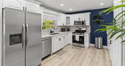 a kitchen with white cabinets and a blue wall at Chicago Vibe Heated Pool 5BR 2BTH in Miami