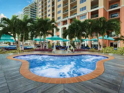 a swimming pool at a resort with palm trees and umbrellas at Marriott's BeachPlace Towers Studio Apartment with Resort Access in Fort Lauderdale