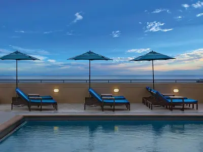 a pool with chairs and umbrellas next to the ocean at Marriott's BeachPlace Towers 2BR Apartment with Resort Access in Fort Lauderdale