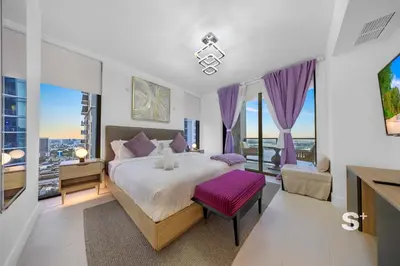 a bedroom with a king sized bed with purple accents at Chic 2-Bedroom Downtown Condo with Breathtaking City & Waterfront Views in Miami