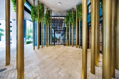 a hallway with gold columns and plants in a building at Sleek 3-BD Downtown Miami Condo with Water & City Views in Miami