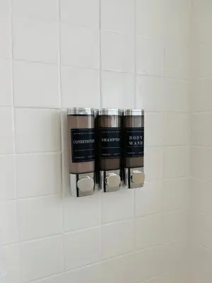 a group of three bottles on a white tiled wall at Beautiful Studio w Amazing View of Miami Skyline in Miami Beach