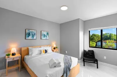 a bedroom with a bed and a chair and a window at Urban Comfort - 20min to Beach & Airport in Miami