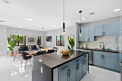 a kitchen with blue cabinets and a dining room at Urban Comfort - 20min to Beach & Airport in Miami