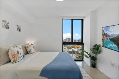 a white bedroom with a large bed and a window at Luxury Pent House with Downtown Views in Miami