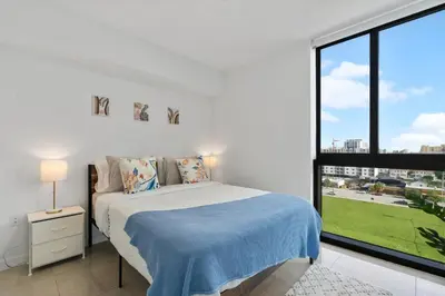 a white bedroom with a bed and a large window at Luxury Pent House with Downtown Views in Miami