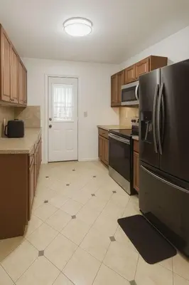 a kitchen with wooden cabinets and a black refrigerator at Casa Rosa Wynwood in Miami