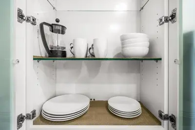 a cupboard with plates and dishes on a shelf at Comfort and Space Fort Lauderdale Miami in Fort Lauderdale