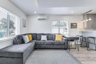 a living room with a gray couch and a kitchen at 8 Mi to Design District Miami Home with Yard in Miami