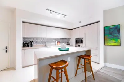 a kitchen with white cabinets and two bar stools at Elegant Beachfront Retreat in Hollywood