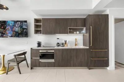 a kitchen with wooden cabinets and a sink and a table at Gale Hotel - Premium Studio W Panoramic City Views in Miami