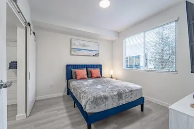 a bedroom with a blue bed and a window at Devereaux Miami Luxury 2 Bedroom Apartment in Biscayne Gardens