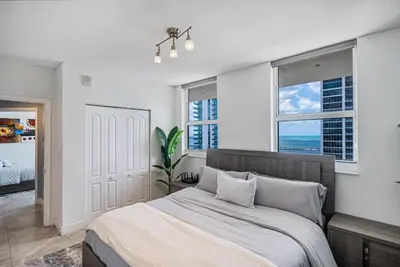 a bedroom with a large bed and two windows at Top Floor Front Facing Penthouse With Breathtaking Views in Miami