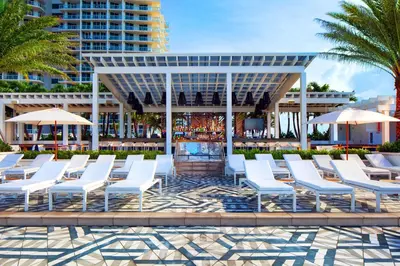 a group of white chairs and umbrellas at a resort at Exclusive Beachfront Condo at W Fort Lauderdale in Fort Lauderdale