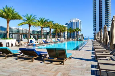 a swimming pool with chaise lounge chairs and palm trees at Modern Condo Retreat with Ample Space in Hollywood