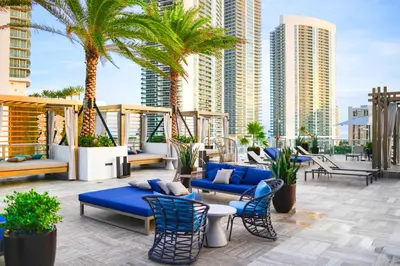 a patio with blue furniture and palm trees and buildings at Modern Condo Retreat with Ample Space in Hollywood