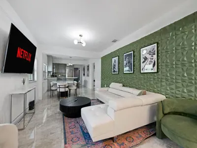 a living room with a white couch and a green wall at The Velvet Palm Midtown Pool and Hot Tub in Miami