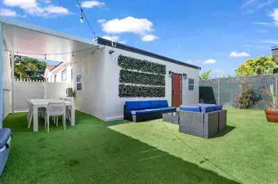 a patio with a table and chairs on a lawn at La Pergola Villa 7 BR PoolHot Tub Location in Miami