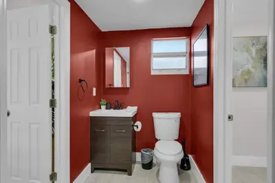 a red bathroom with a toilet and a sink at La Pergola Villa 7 BR PoolHot Tub Location in Miami