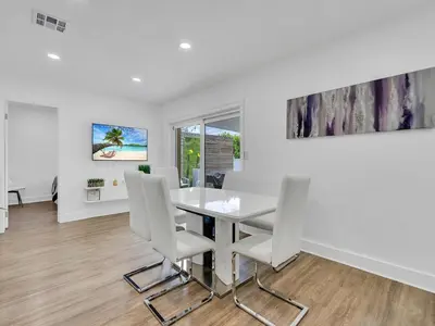 a dining room with a glass table and white chairs at Canal Views from Pool w BBQ and Pit Miami Escape in Kendale Lakes