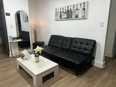 a living room with a black couch and a table at Canal Views from Pool w BBQ and Pit Miami Escape in Kendale Lakes