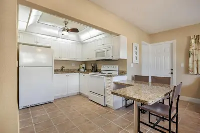 a kitchen with white cabinets and a table with chairs at Coconut Bay Resort in Fort Lauderdale