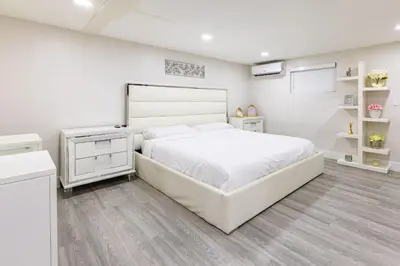 a white bedroom with a large white bed and wooden floors at Stylish 3BR Home - BBQ & Near Top Attractions in Miami Gardens