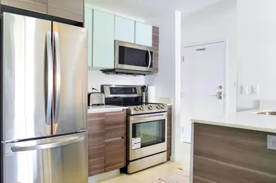 a kitchen with a stainless steel refrigerator and a microwave at Contemporary Condo in Wynwood w Free Parking in Miami