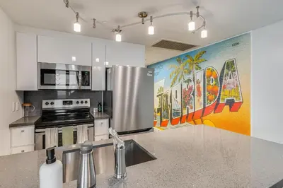 a kitchen with a stainless steel refrigerator and a mural at Bright 1BR in Coconut Grove King Bed Views Pool and Parking in Miami