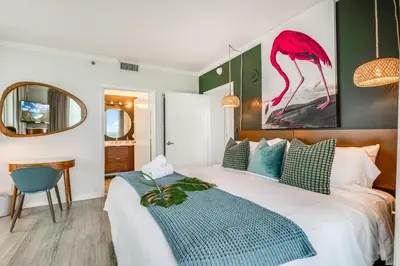 a bedroom with a bed and a pink flamingo painting on the wall at Bright 1BR in Coconut Grove King Bed Views Pool and Parking in Miami