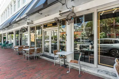 a restaurant with tables and chairs outside of a building at Bright 1BR in Coconut Grove King Bed Views Pool and Parking in Miami