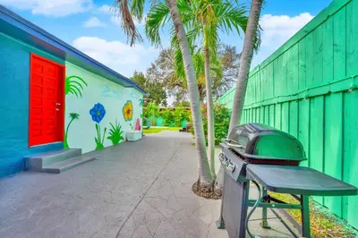 a trash can next to a building with palm trees at La Casa Flora Private PoolHot tubSleeps 18 in Miami