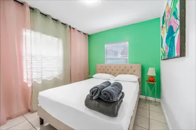 a bedroom with a white bed and a green wall at La Casa Flora Private PoolHot tubSleeps 18 in Miami