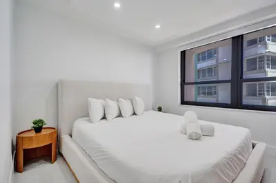 a white bedroom with two beds and a window at Bright Beachside 4 Bedrooms 2 Bathrooms Condo Pools Gym and Sauna Access 616 in Miami Beach