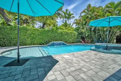 a swimming pool with an umbrella and a patio at Shady Palms - Pool & Jacuzzi in Fort Lauderdale