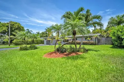 a house with palm trees in front of a yard at Shady Palms - Pool & Jacuzzi in Fort Lauderdale