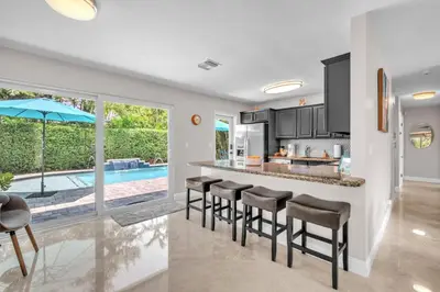 a kitchen and living room with a bar with stools at Shady Palms - Pool & Jacuzzi in Fort Lauderdale