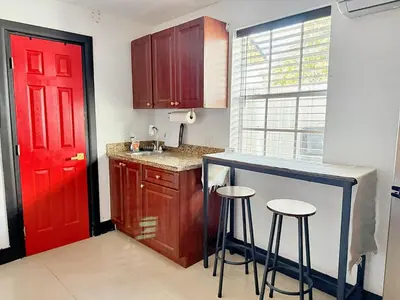 a kitchen with a red door and two bar stools at Cottage with Hot Tub, Private Firepit, Entrance, Parking BBQ in Miami Gardens