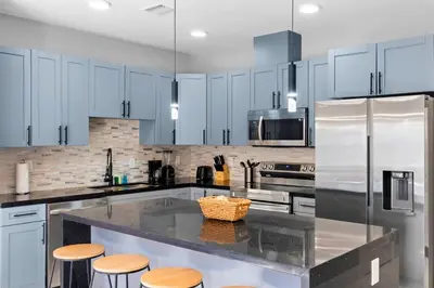 a kitchen with white cabinets and a counter with stools at Comfortable Townhouse - Free Parking Included in Miami
