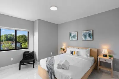 a bedroom with a bed and a chair and a window at Stylish Townhouse Steps from Wynwood in Miami