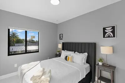 a bedroom with a large white bed with a window at Stylish Townhouse Steps from Wynwood in Miami