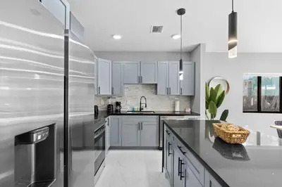 a kitchen with white cabinets and a stainless steel refrigerator at Stylish Townhouse Steps from Wynwood in Miami