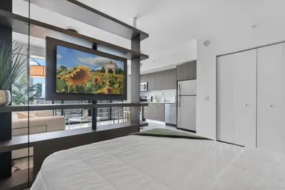 a bedroom with a television on a wall with a kitchen at High-Rise Luxury Condo in Downtown Miami with Ocean Views in Miami