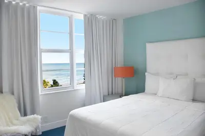 a bedroom with a bed and a window with the ocean at Seacoast Suites on Miami Beach in Miami Beach