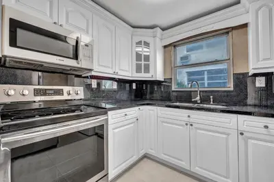 a kitchen with white cabinets and stainless steel appliances at The Pink Palm Little Havana Pool & Hot Tub in Miami