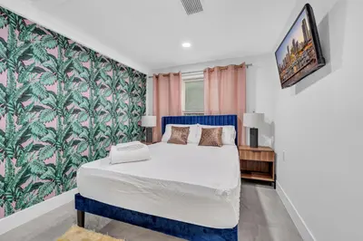 a bedroom with a large bed and a wall mural at The Pink Palm Little Havana Pool & Hot Tub in Miami