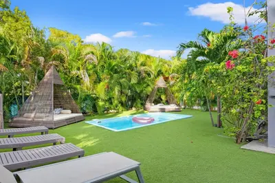 a backyard with a pool and green grass and trees at The Purple Paradise PoolHot Tub Little Havana in Miami