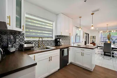 a kitchen with white cabinets and a dining room at Villa Las Olas Designed with you in mind! in Fort Lauderdale